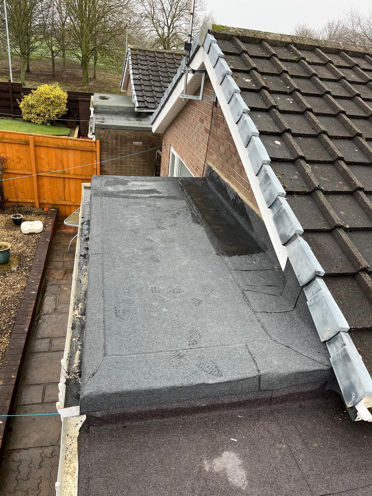 Flat felt roof dressed with new lead flashing up against a slate pitched roof